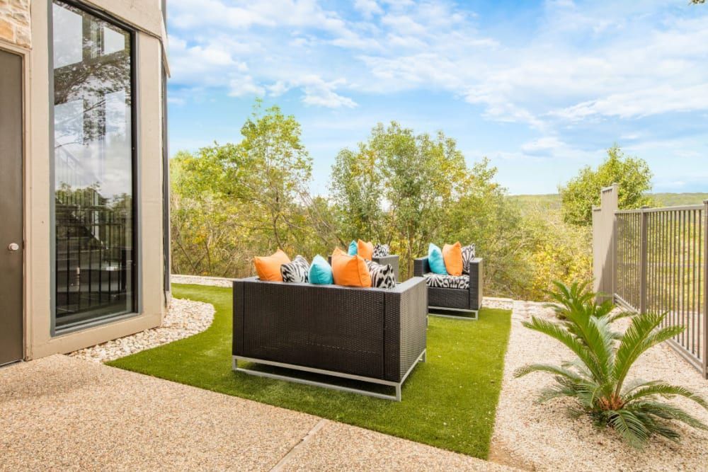 A patio with a couch and chairs on a lush green lawn at Marquis at Treetops in Northwest Austin, TX.
