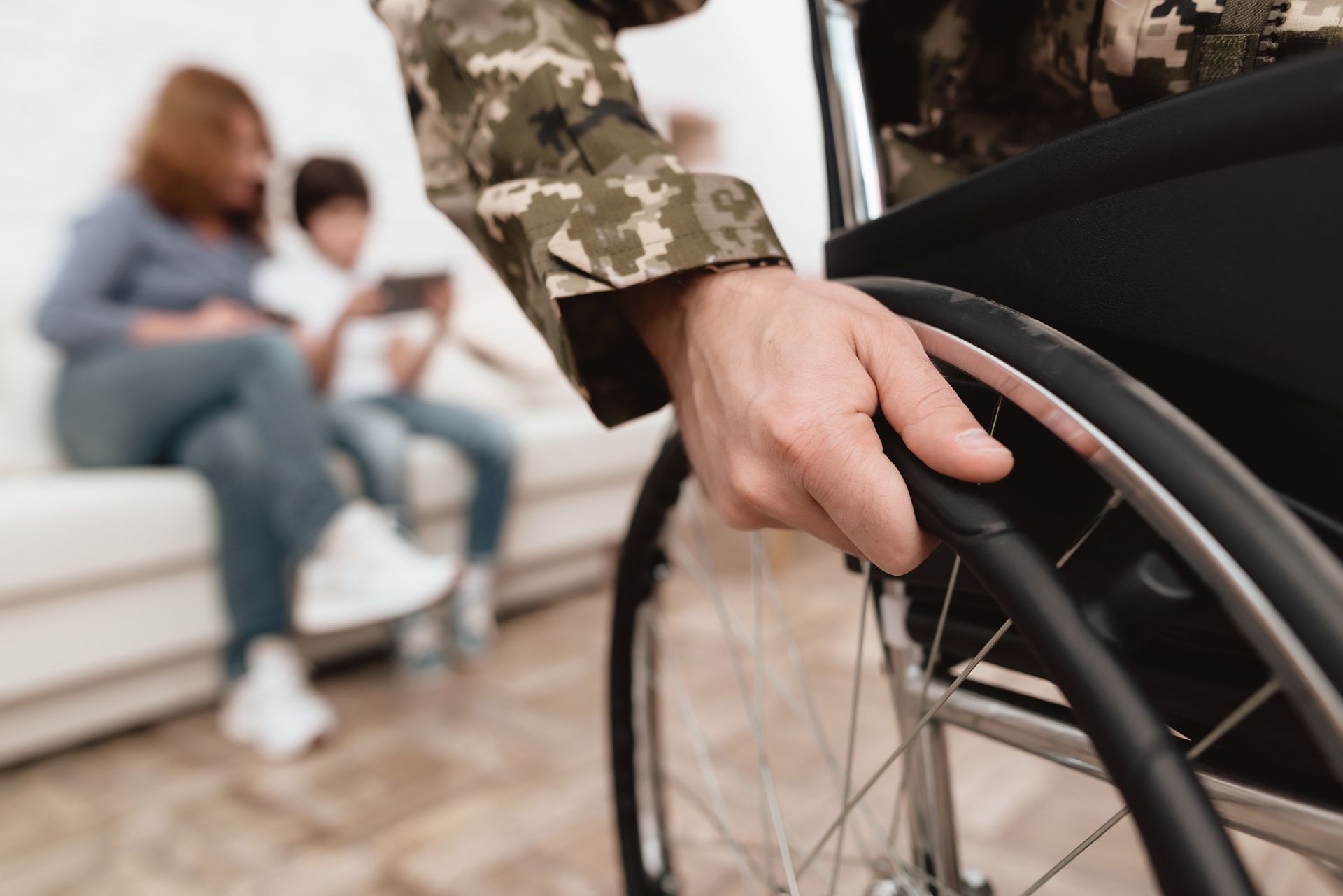 A soldier is sitting in a wheelchair with his family in the background.