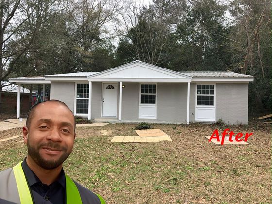 A man is standing in front of a house that has been remodeled.