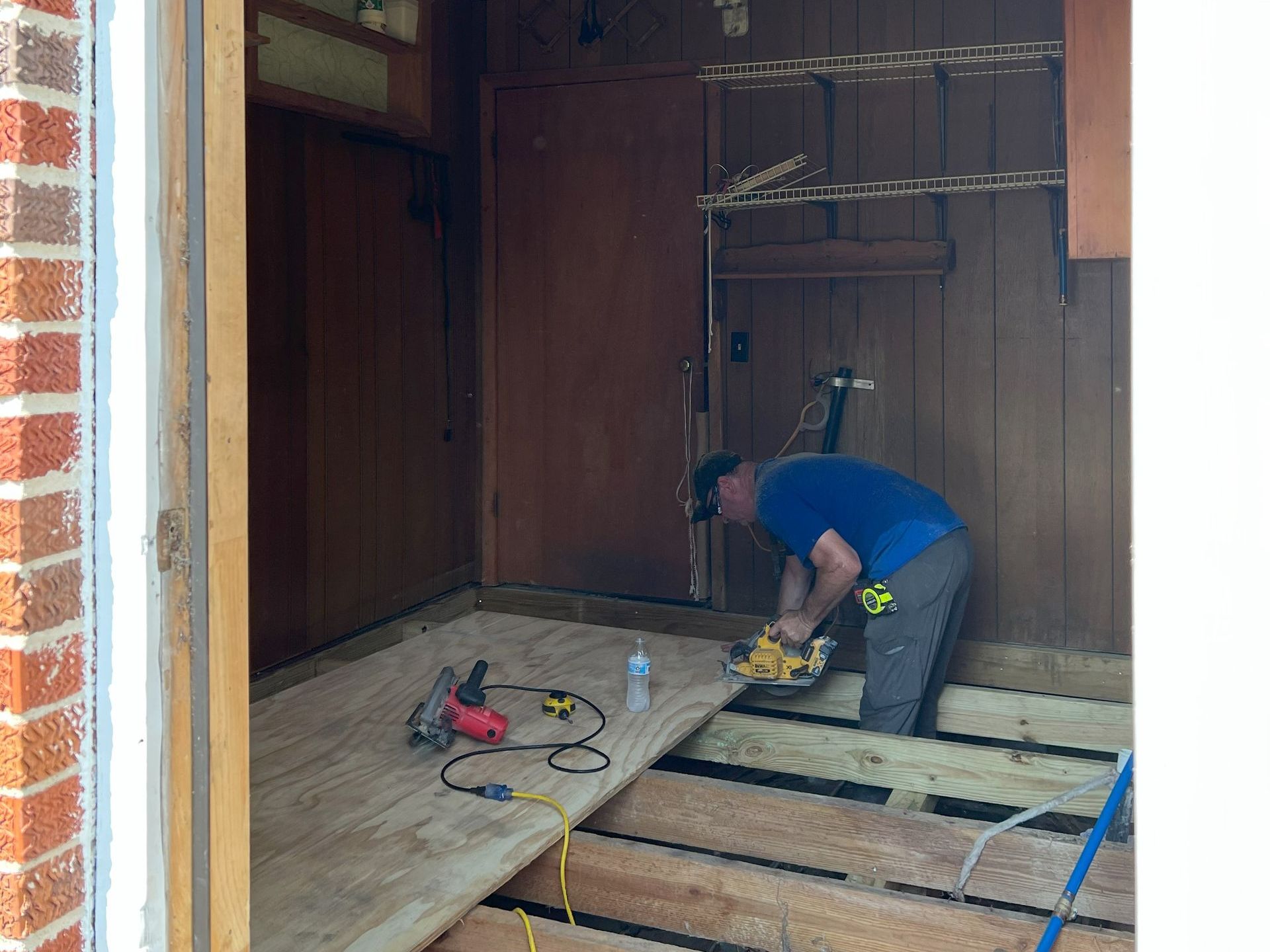 A man is working on a wooden floor in a room.