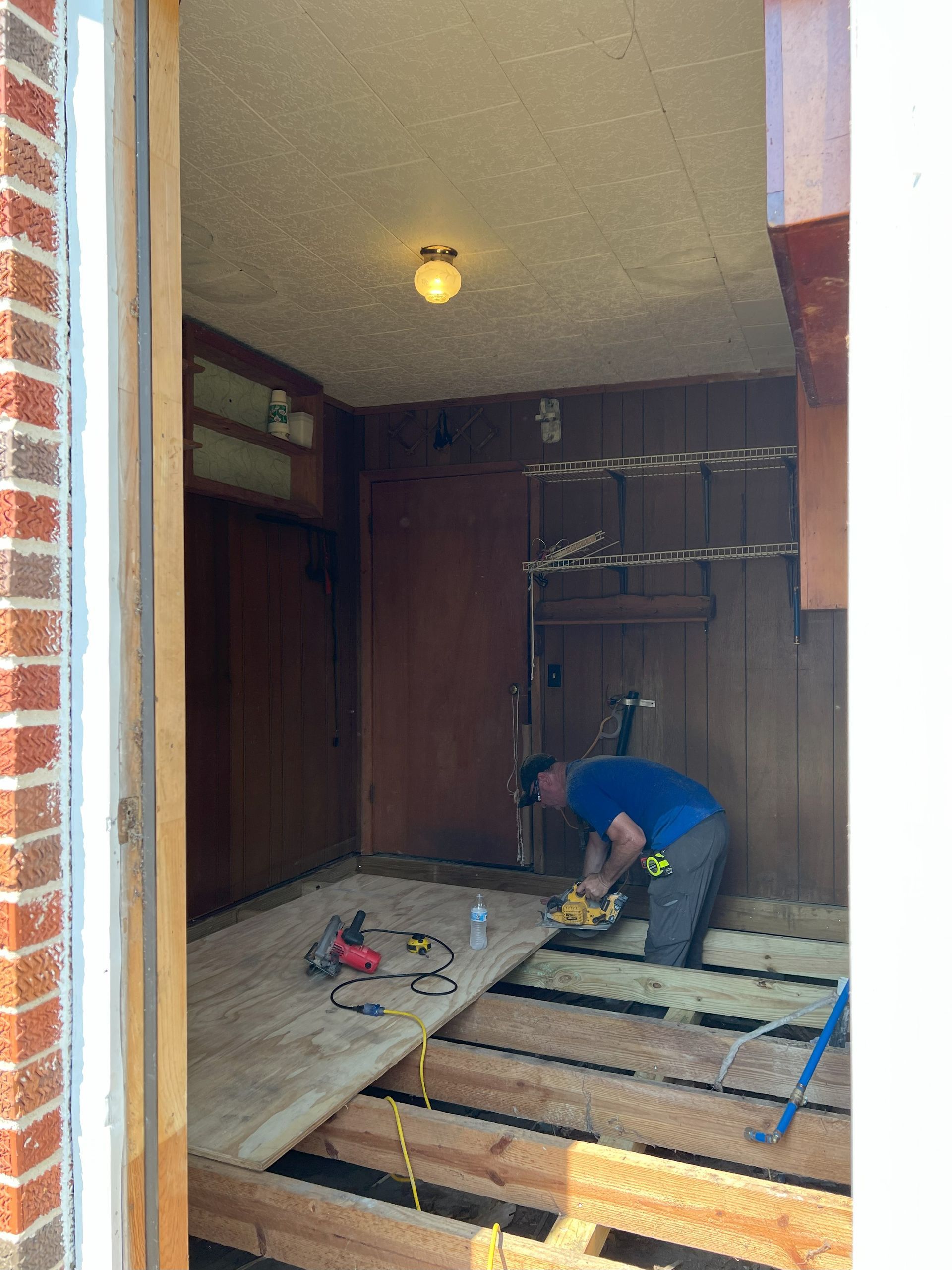 A man is working on a wooden floor in a room.