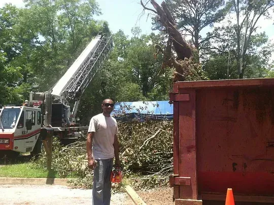 A man is standing in front of a red dumpster next to a fire truck.