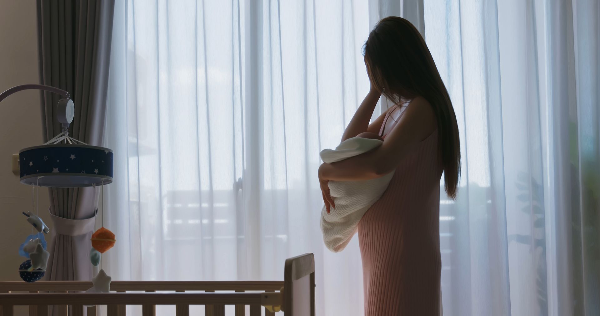 Woman holding baby by window in nursery.
