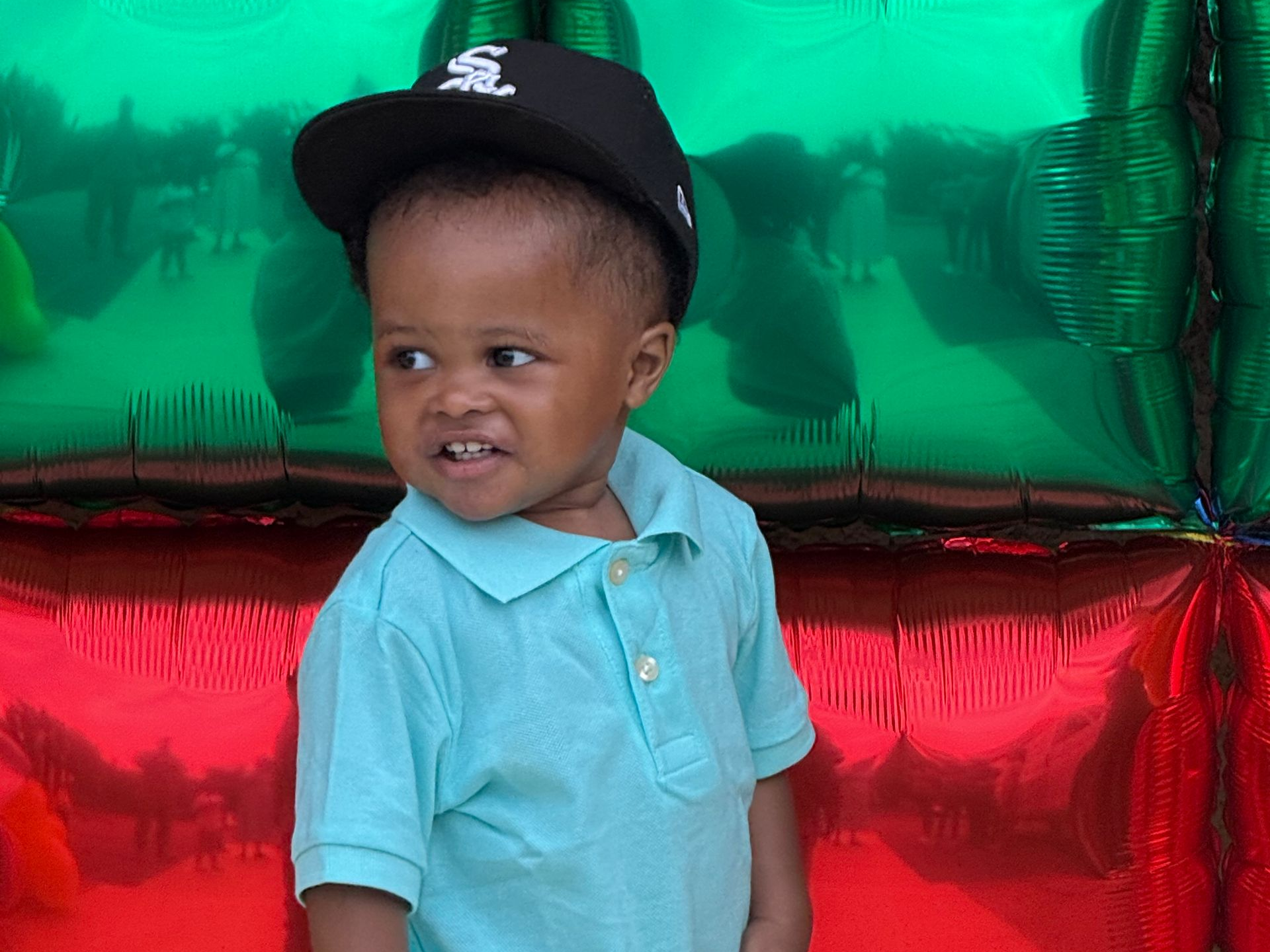 A young girl playing at a toy kitchen in a brightly colored indoor play area with other children.
