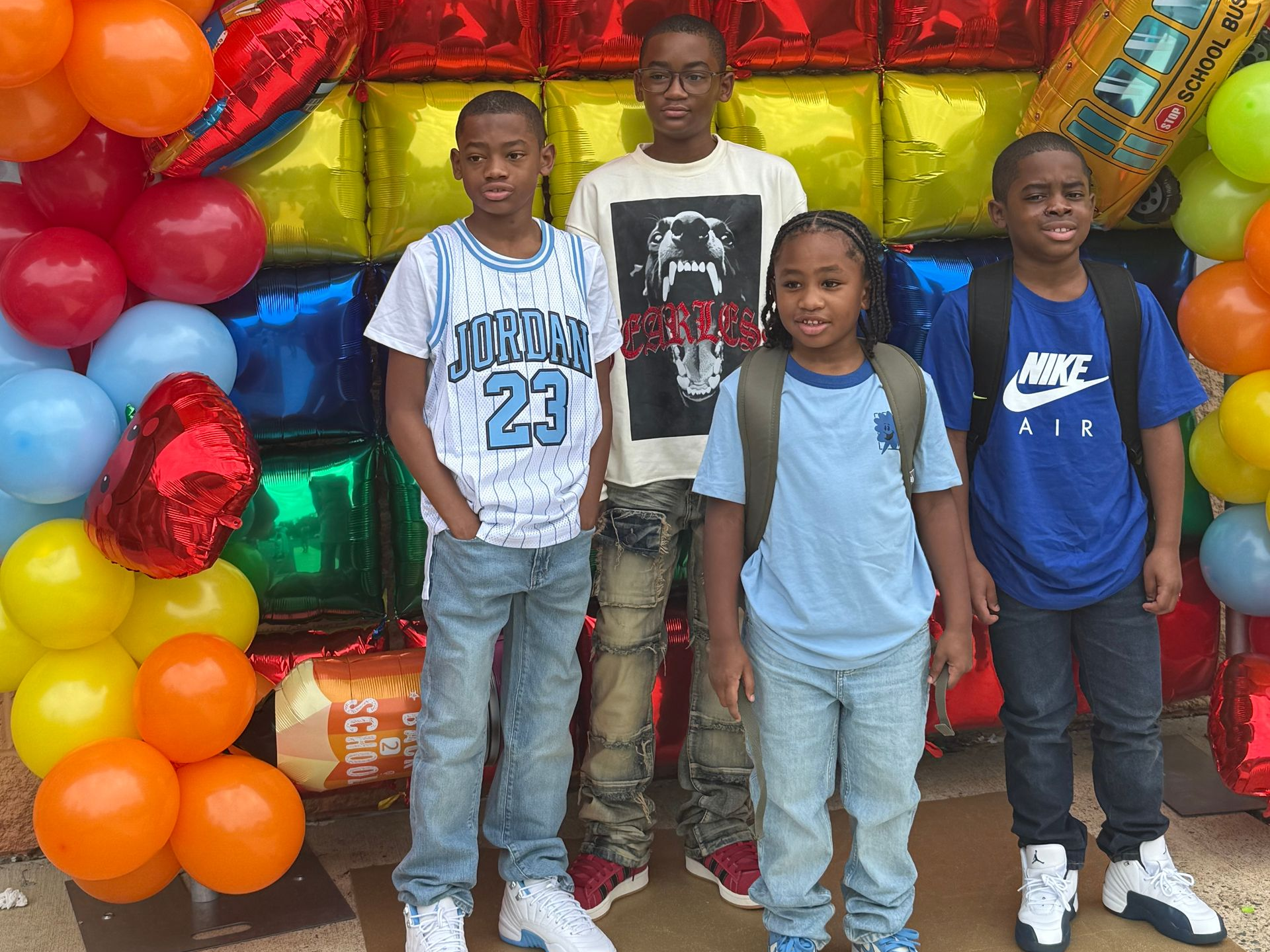 A therapist kneels with a young girl playing with wooden blocks on a patterned rug in a playroom.