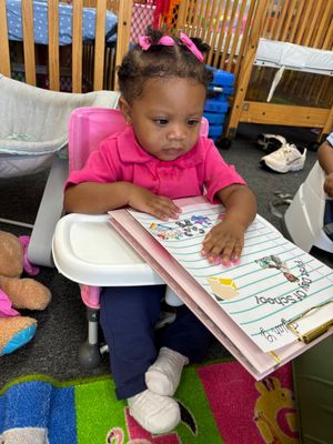 Young child sitting at a table, cutting yellow paper with scissors in a bright room.