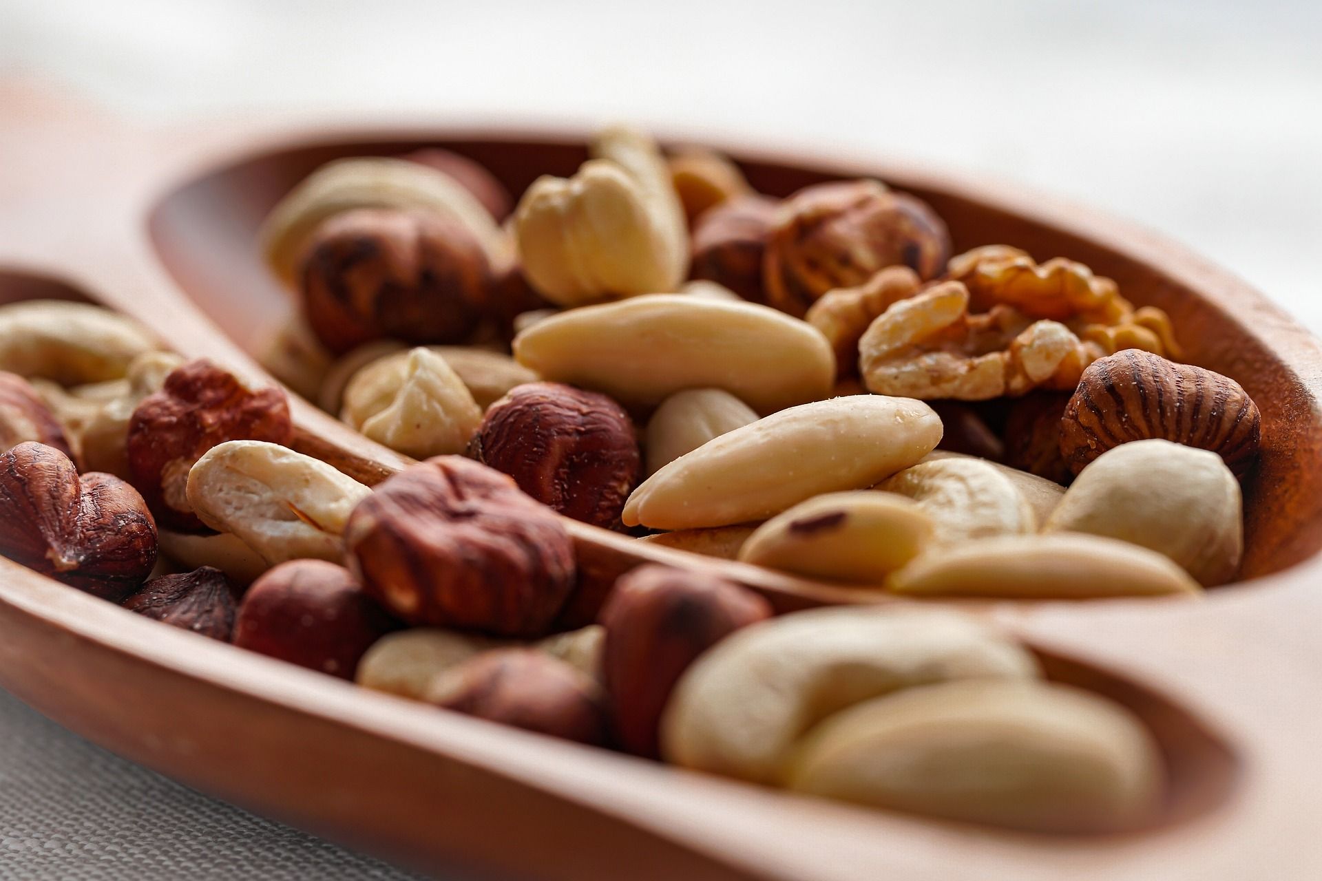 A wooden bowl filled with different types of nuts.