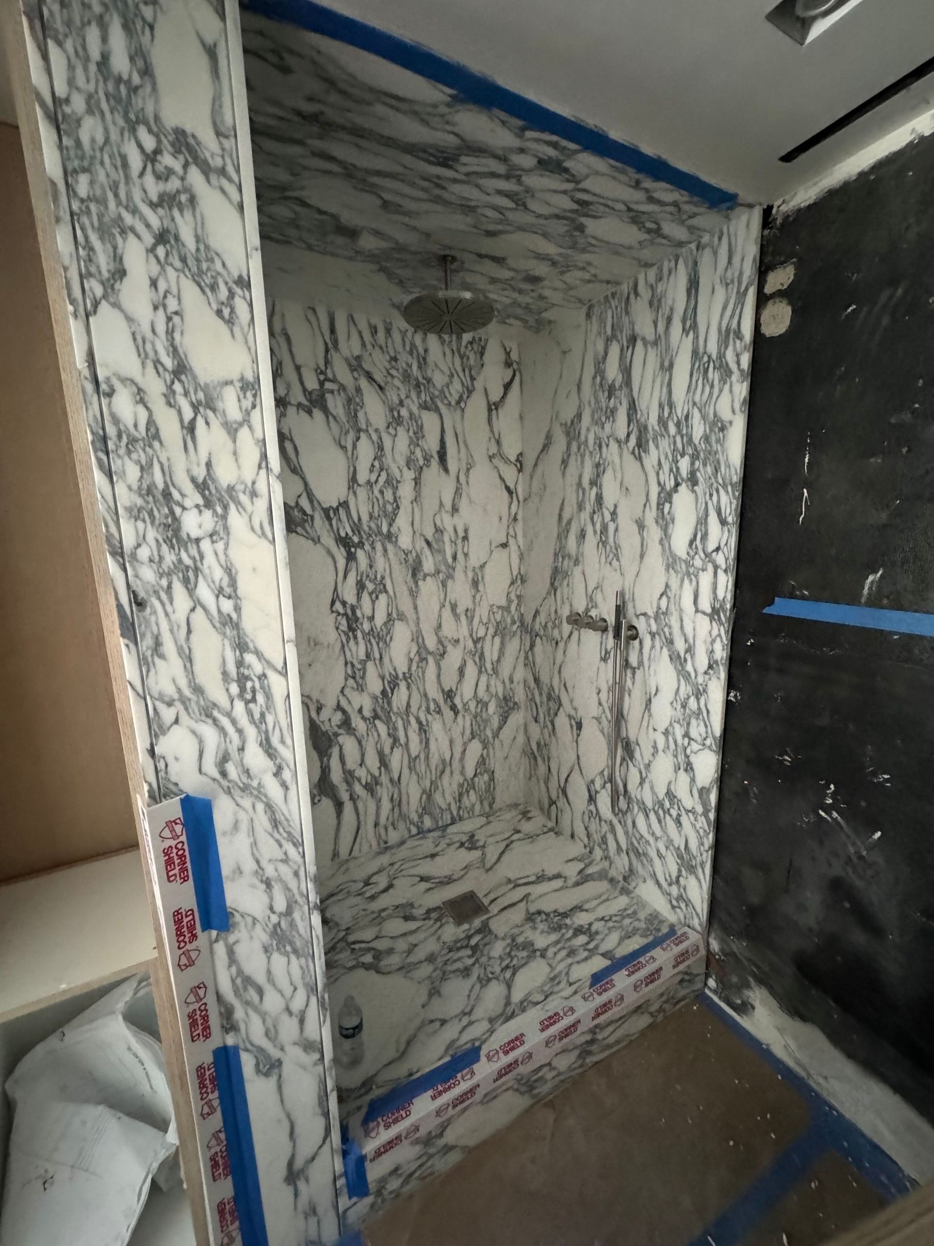 A bathroom with marble walls and a shower stall