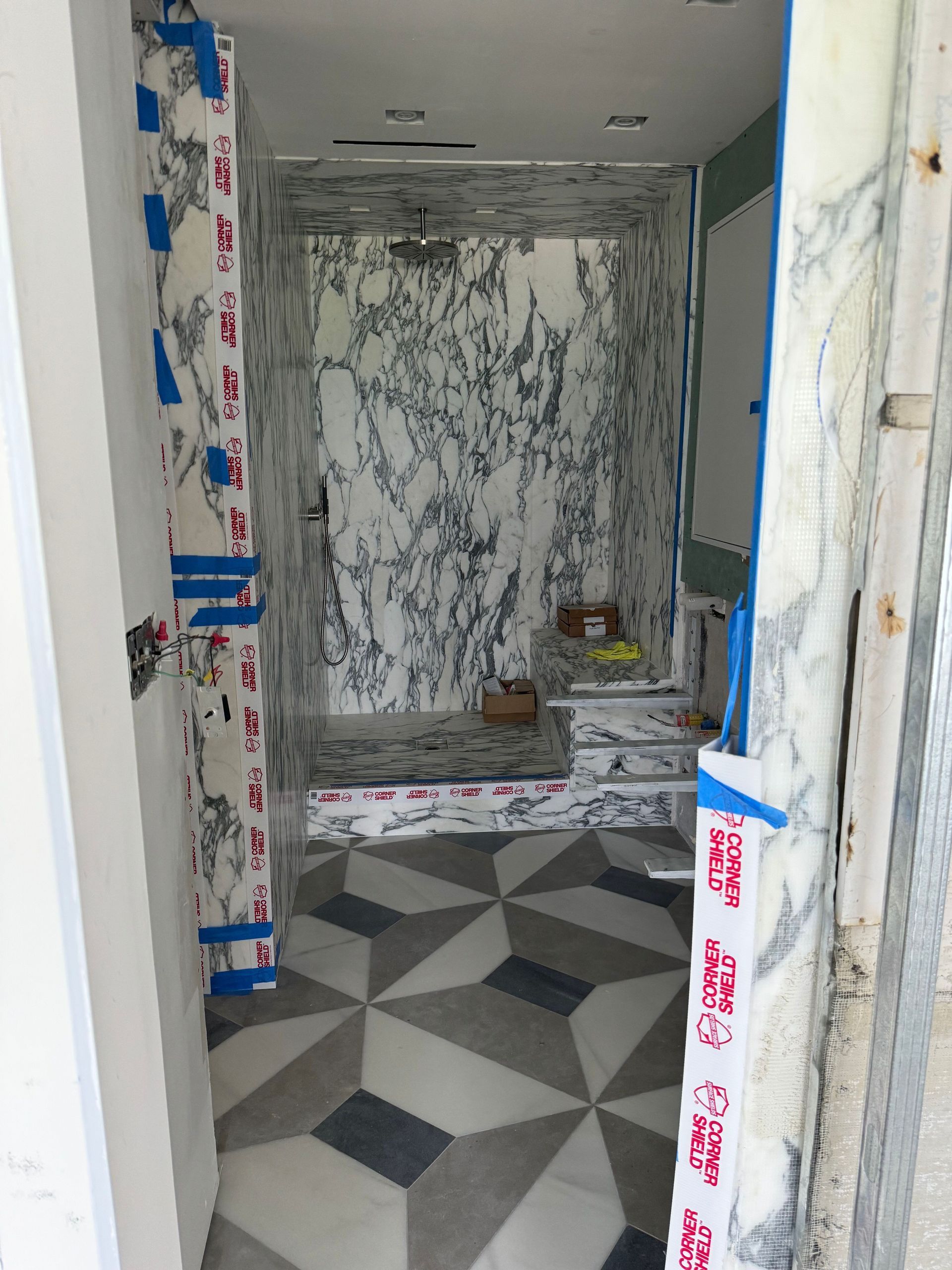 A bathroom with marble walls and a checkered floor is being remodeled.