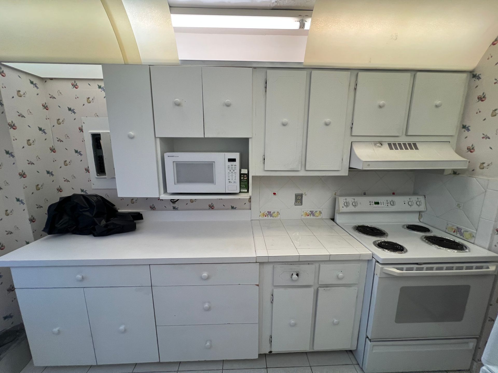 Kitchen undergoing renovation with upper cabinets, fridge, and dishwasher. Walls are damaged.