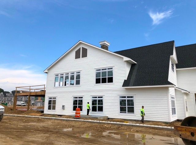 A large white house with a black roof is being built.