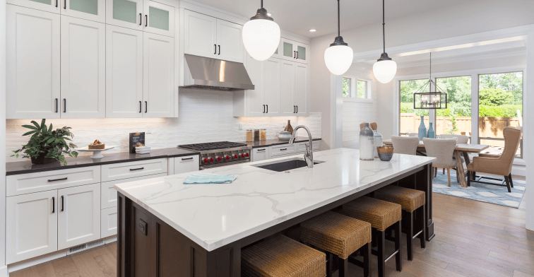A kitchen with white cabinets and a large island in the middle.