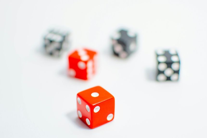 Five dice on a white surface, with one red die in focus and others blurred in the background