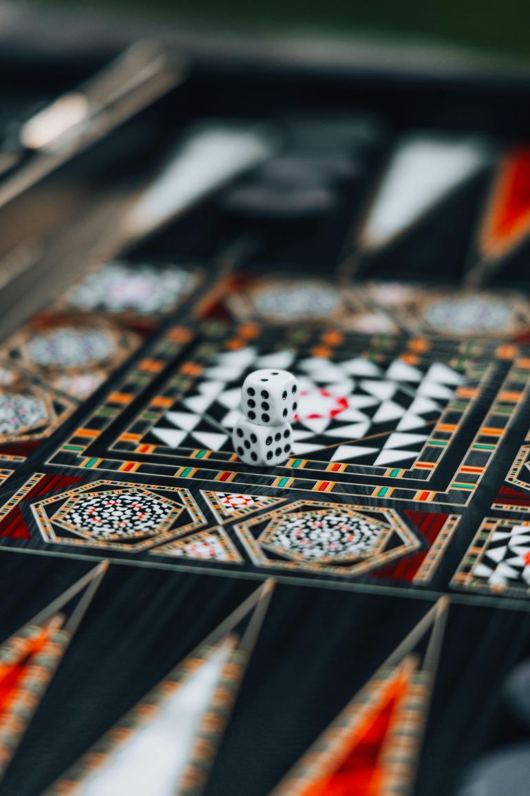A patterned board with dice on a black, white, and orange game surface.