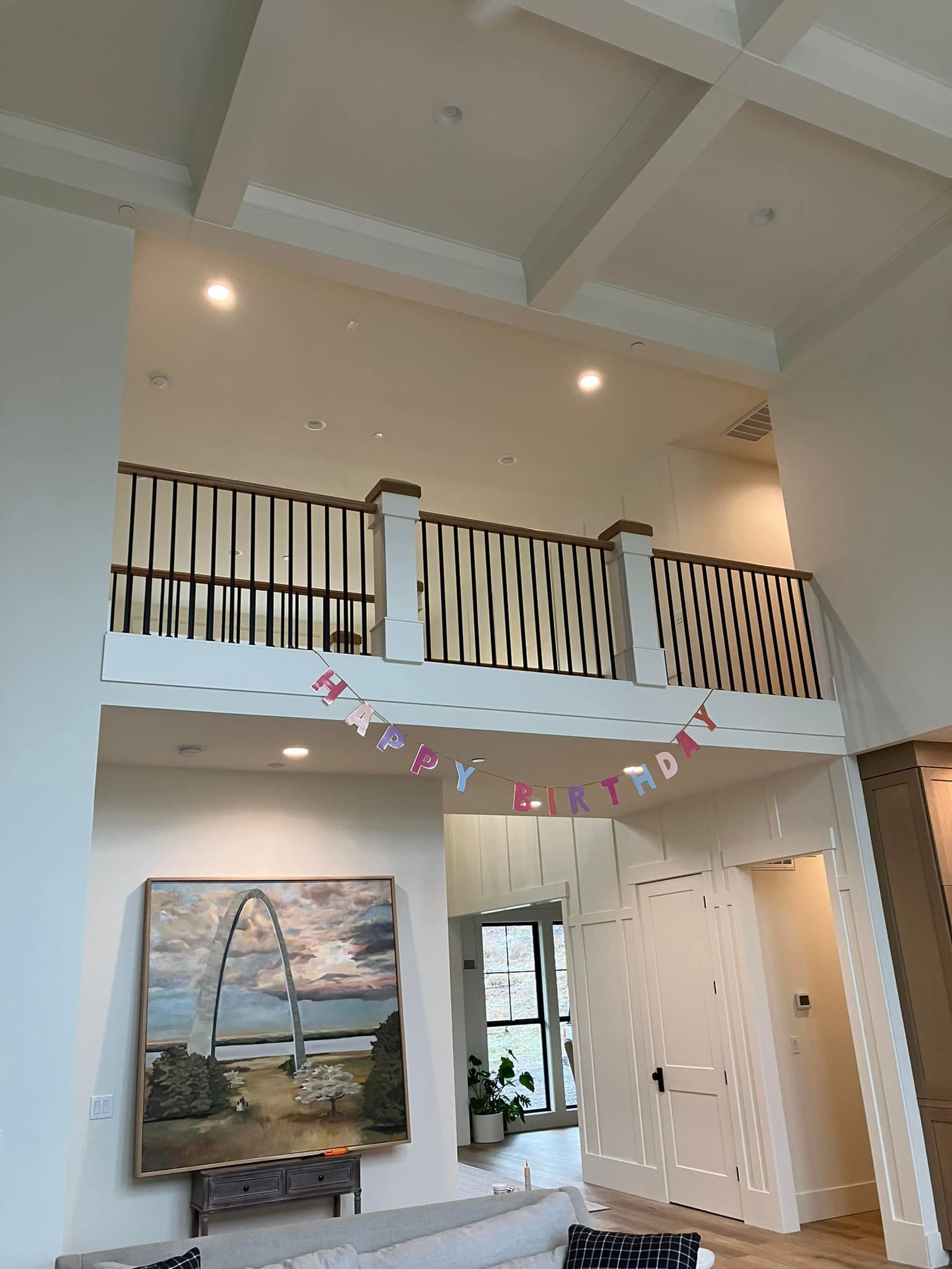 A large living room with a high ceiling, a balcony railing with a 