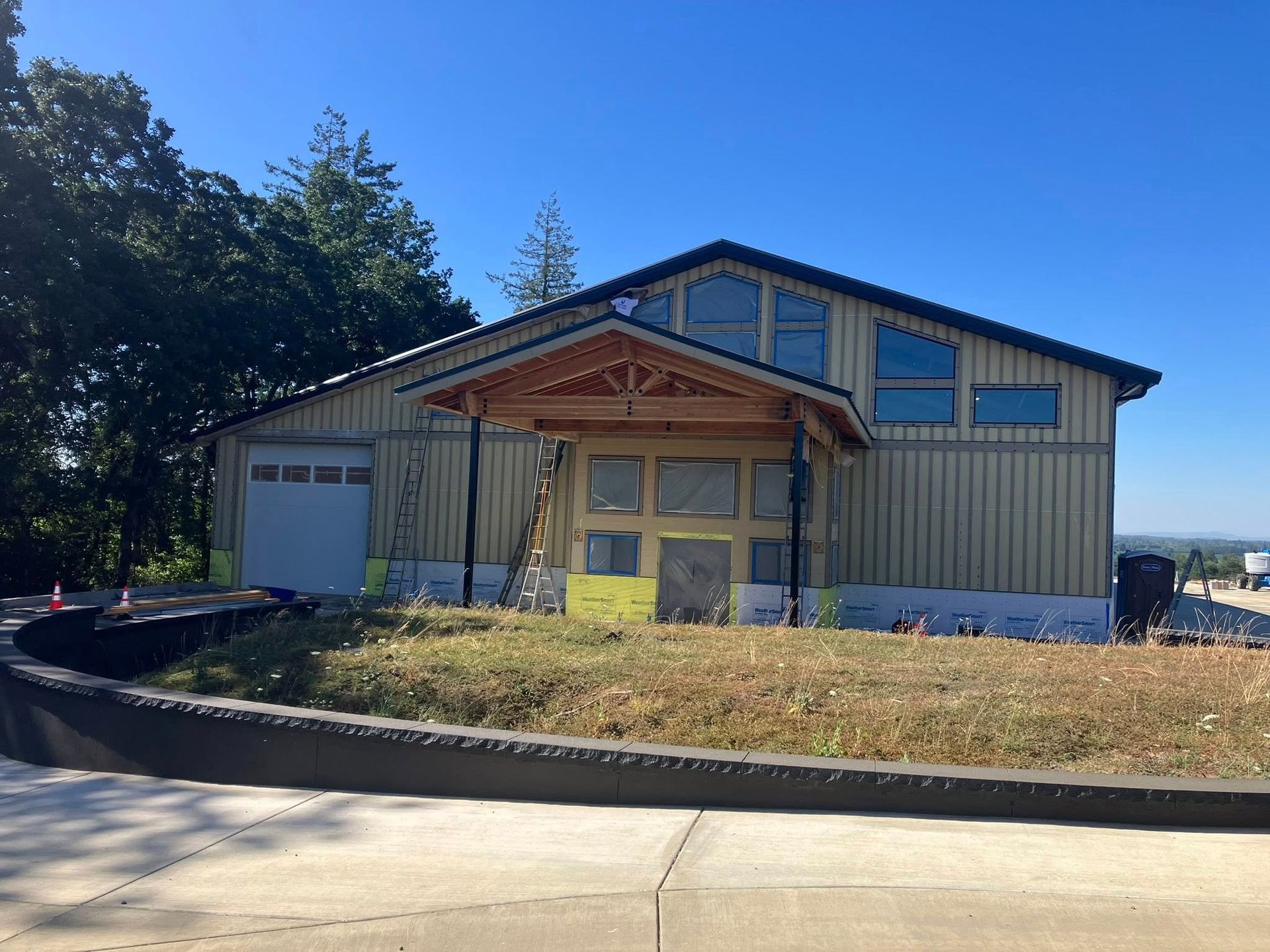 A tan, single-story building with a wooden entrance porch and a garage under a clear blue sky.