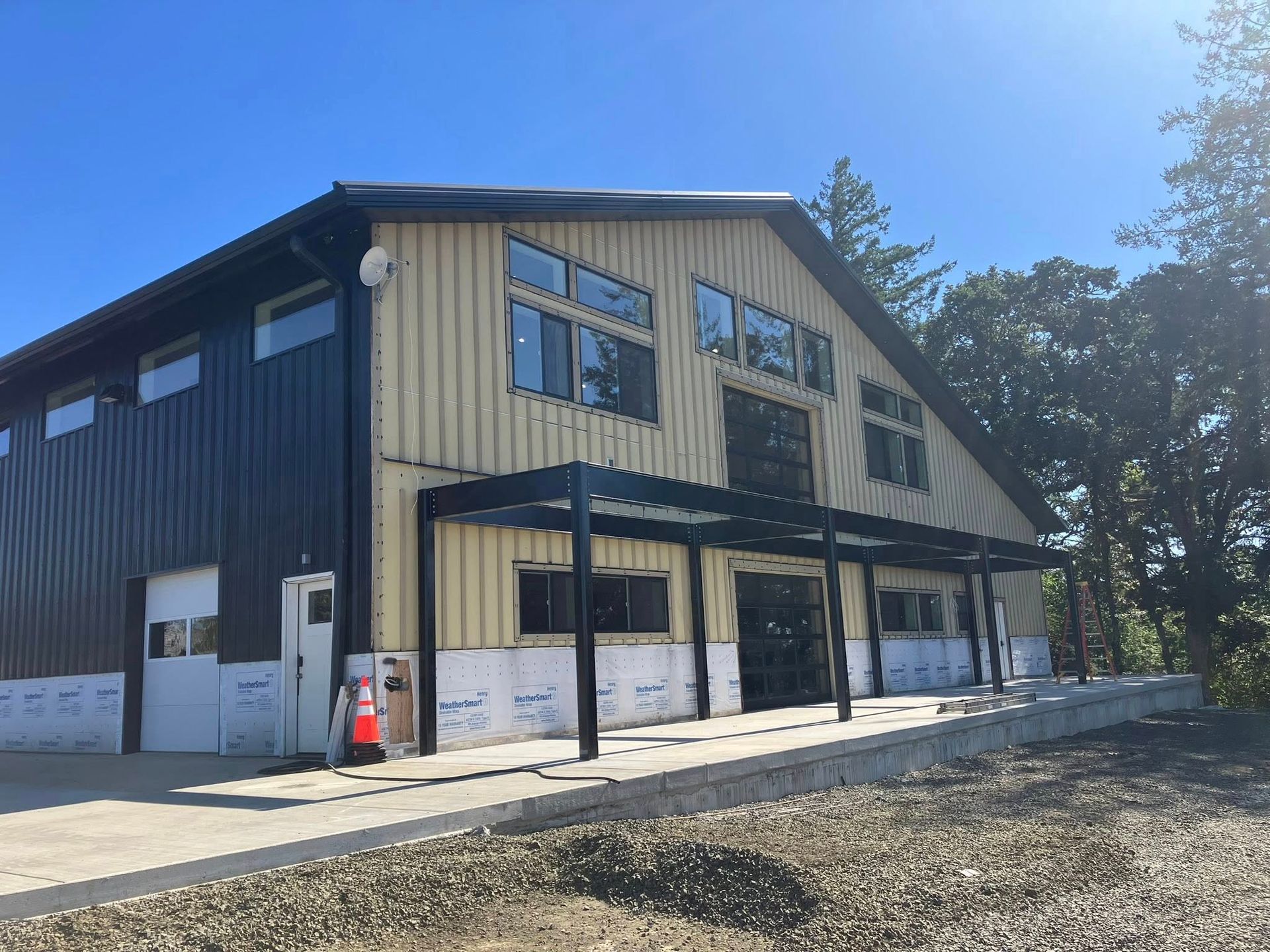 A two-story commercial building with black siding on the left and beige metal walls, featuring a black covered entryway.