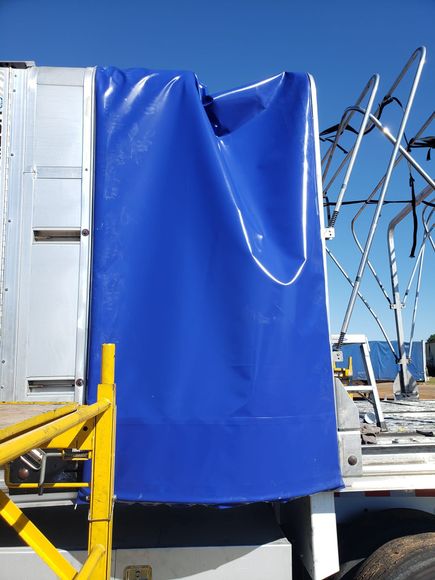 Blue tarp covering equipment on a truck, a yellow scaffold in the foreground.
