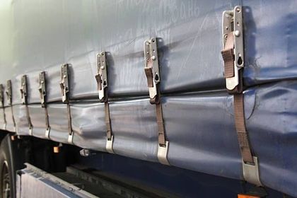 Blue truck side with fastened straps securing the tarp.