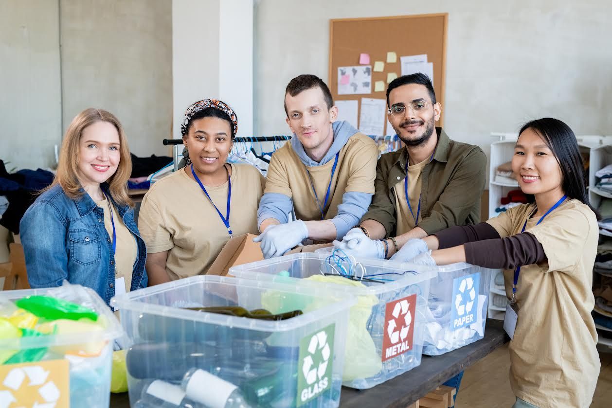Five volunteers smiling, sorting items into recycling bins for full property cleanouts