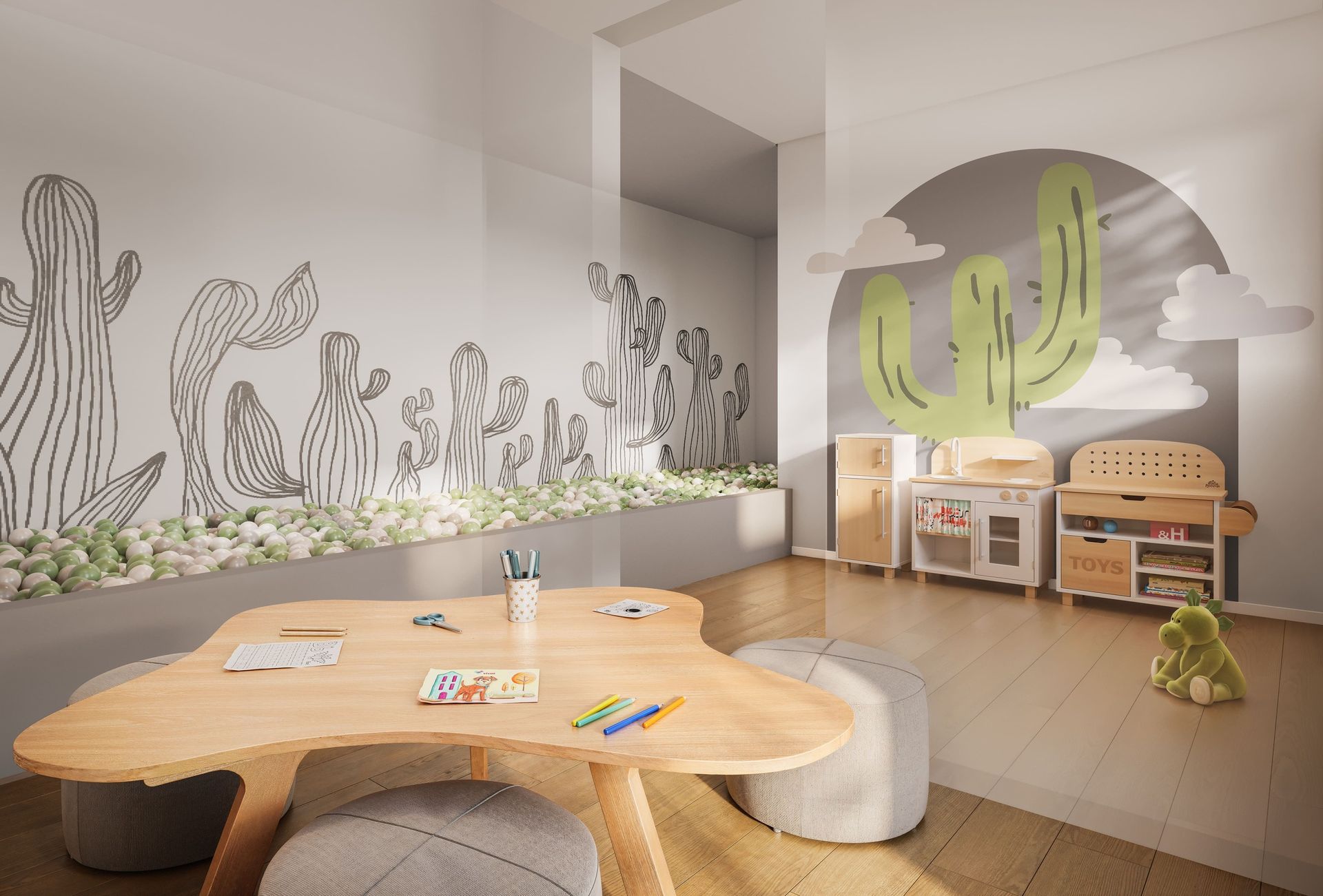 Sala de jogos com mural de cactos, mesa de madeira, cozinha de brinquedo e bicho de pelúcia verde.