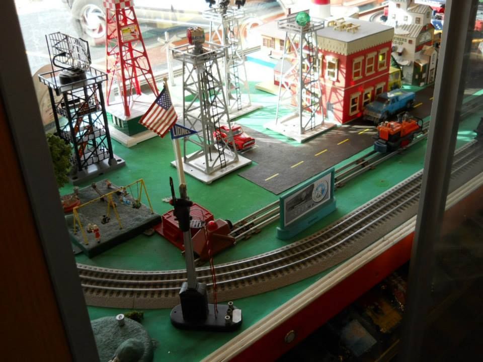A toy train set is sitting on a table in front of a window.