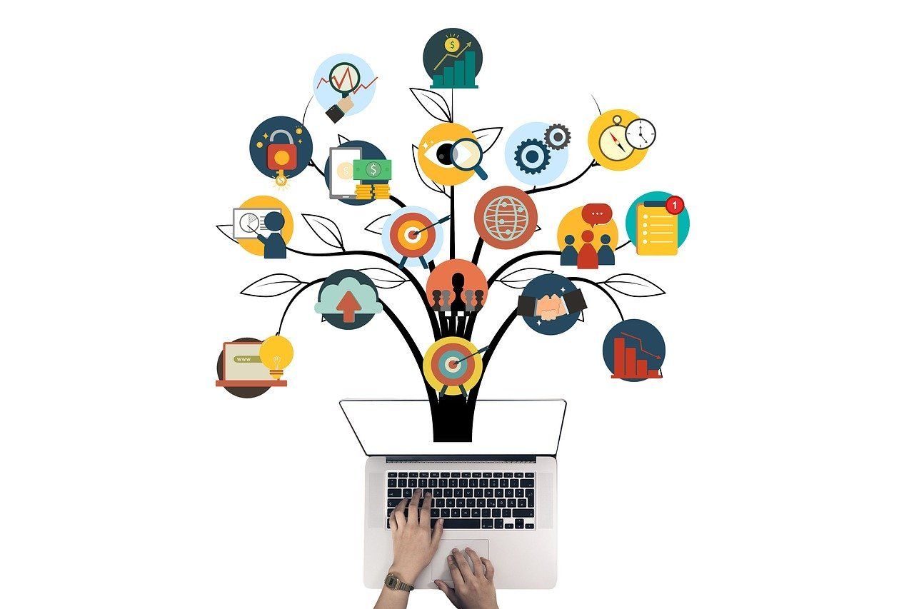 A person is typing on a laptop computer with a tree growing out of it.