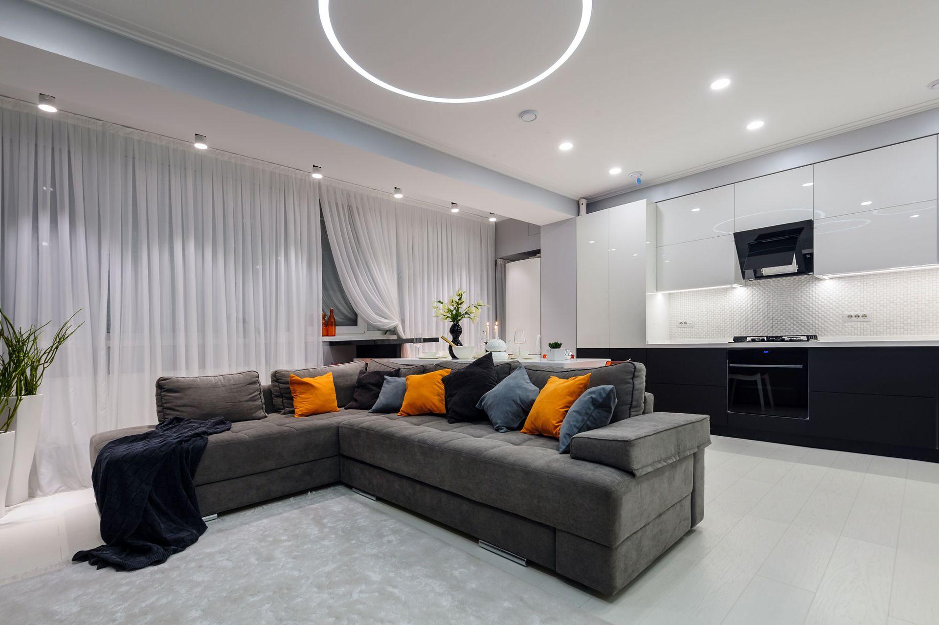 A living room with a large sectional couch and a kitchen.