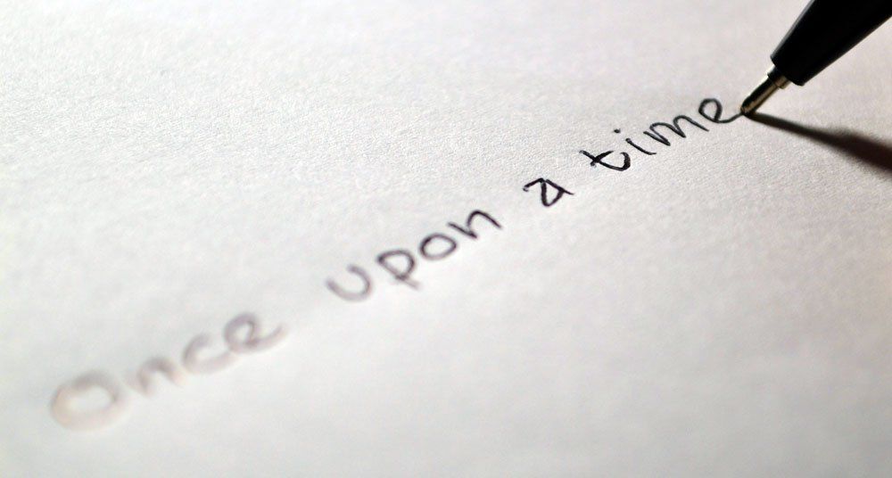 A pen is writing the word once upon a time on a piece of paper.