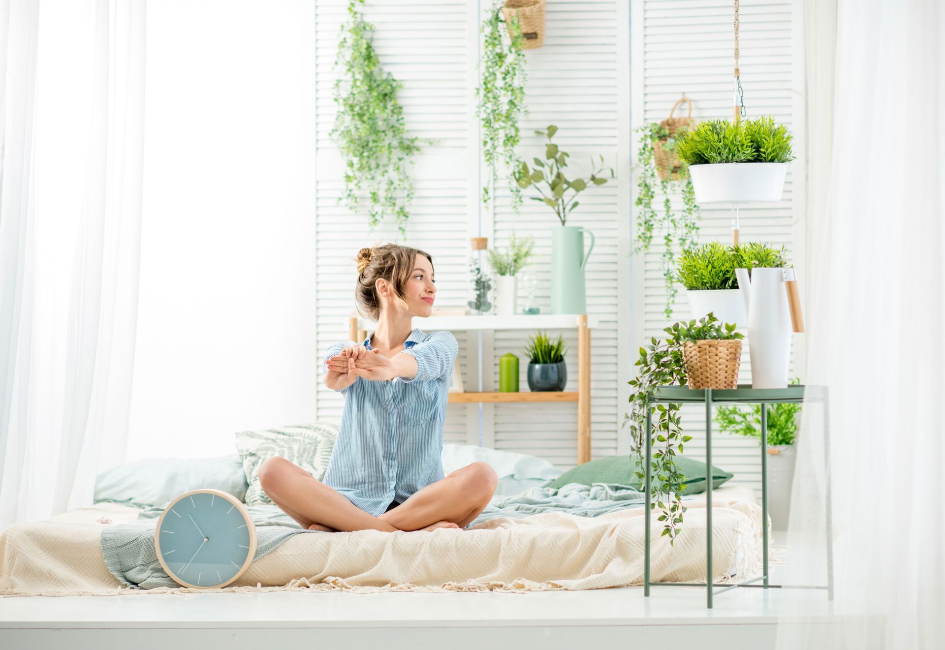 A woman is sitting on a bed talking on a cell phone.