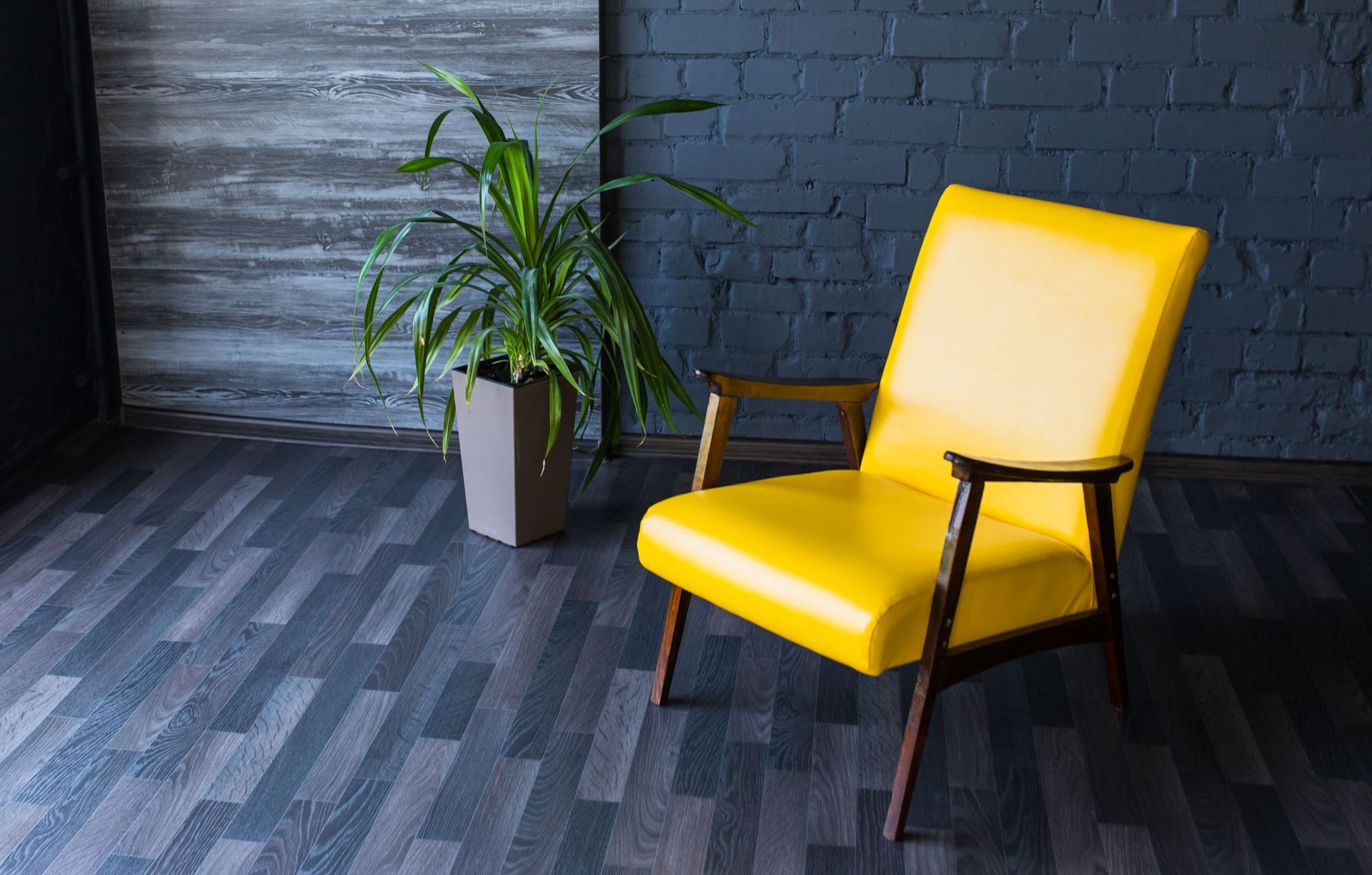 A yellow chair is sitting in a room next to a potted plant.