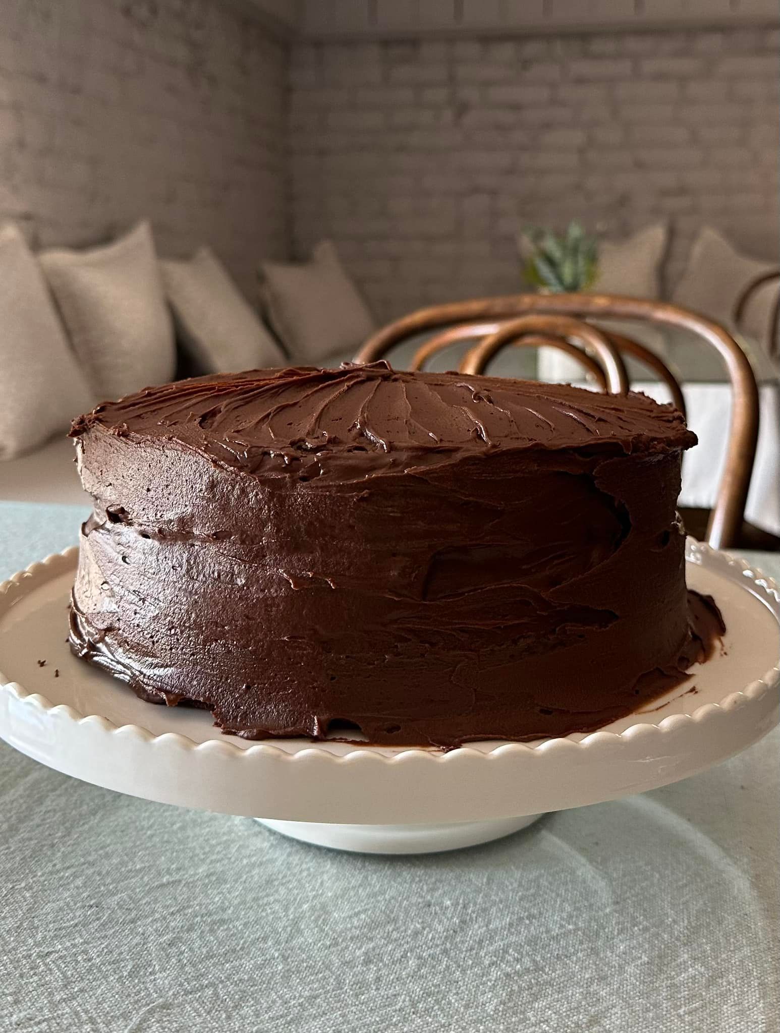 A chocolate cake is sitting on a white plate on a table.