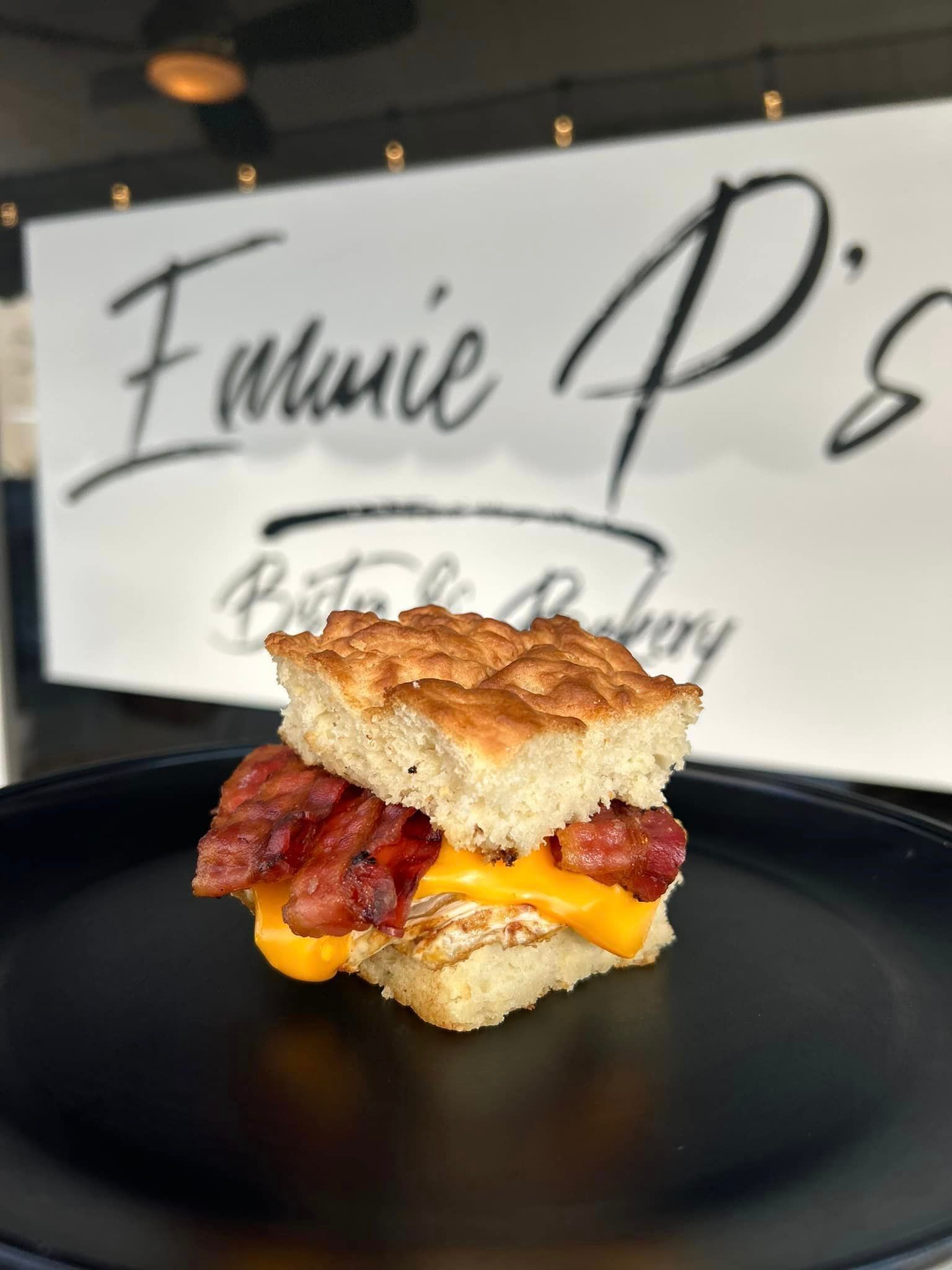 A biscuit sandwich with bacon and cheese on a black plate
