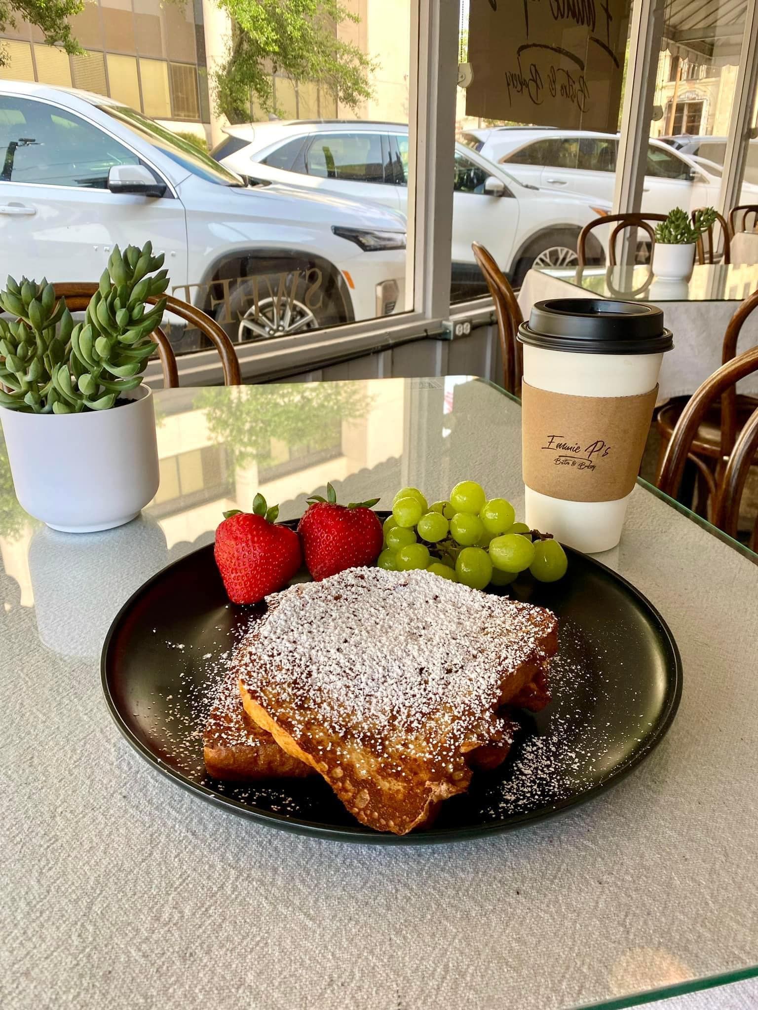 A plate of french toast with powdered sugar and grapes on a table.