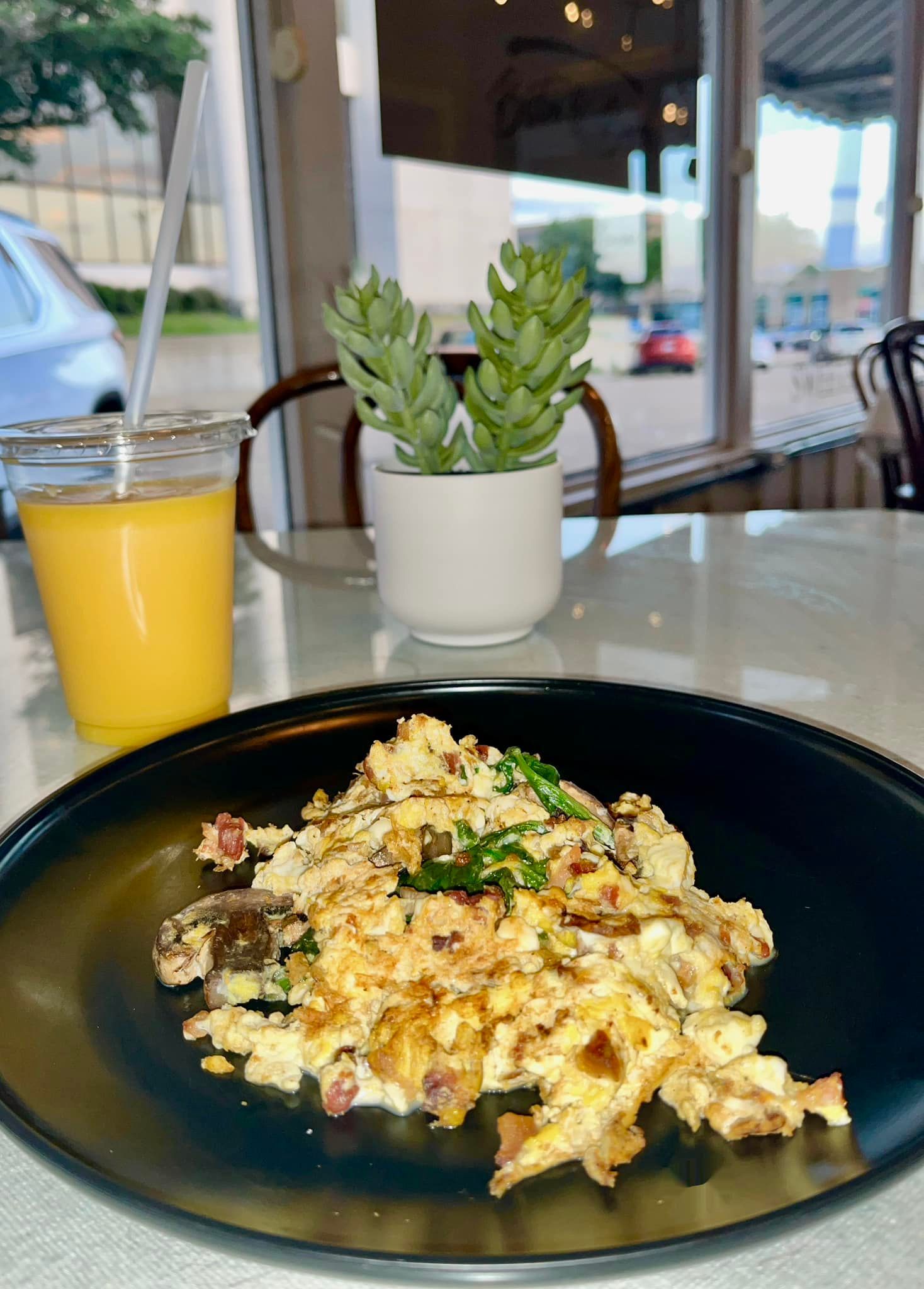 A plate of food and a cup of orange juice on a table.