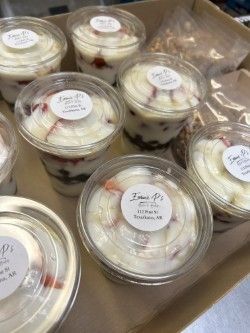 A box filled with a variety of desserts in plastic cups.