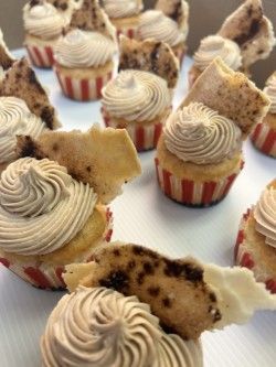 A bunch of cupcakes with frosting on them are sitting on a table.
