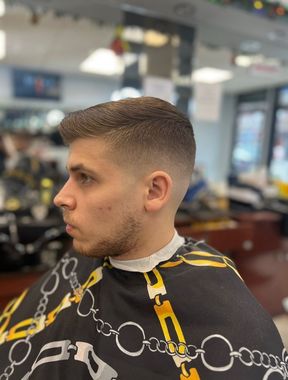 Man's neck and back of head with a faded haircut, in a barbershop setting.
