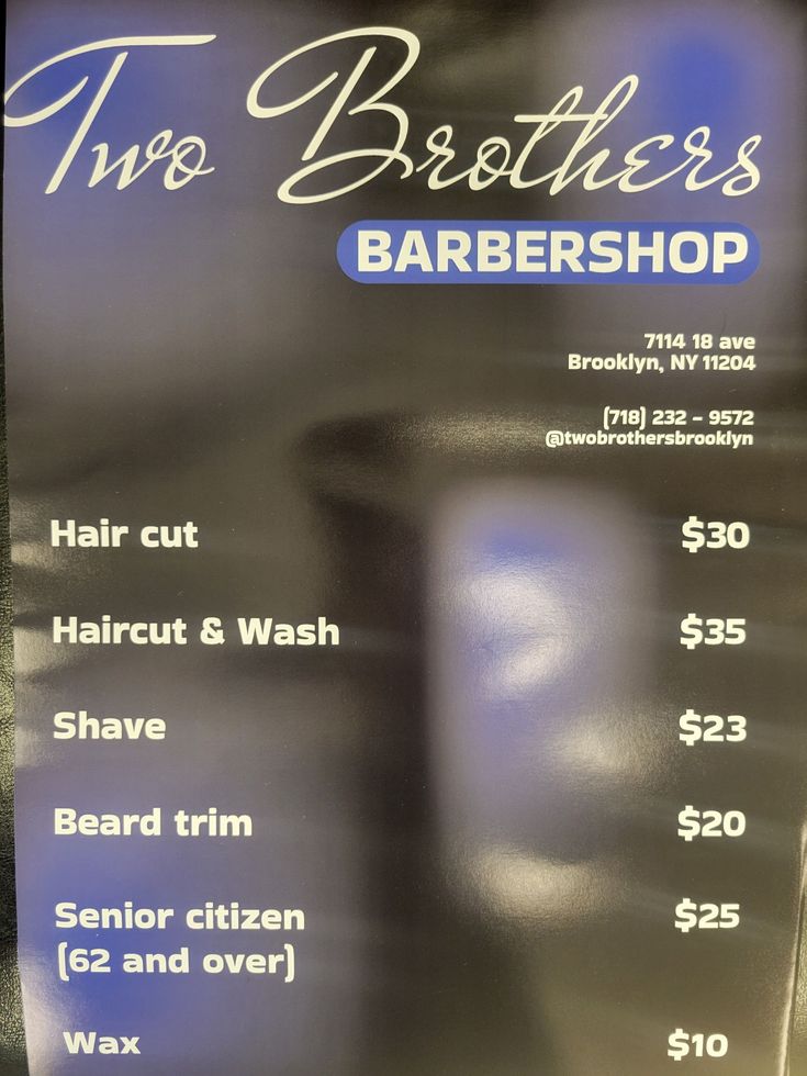 Man in a barber chair with a faded haircut, wearing a white t-shirt and glasses.