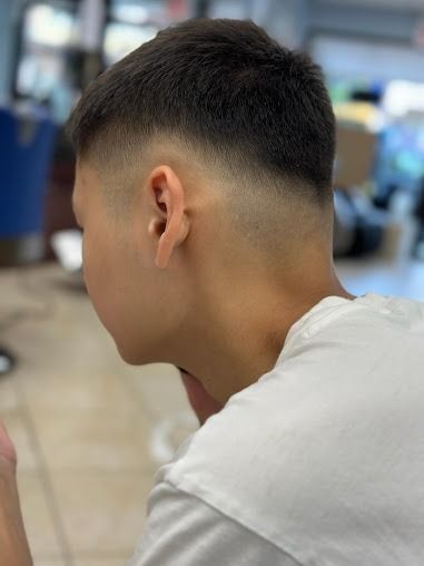 Man with faded haircut, back view. Dark hair on top, fading to skin near ears. He's wearing a white shirt.