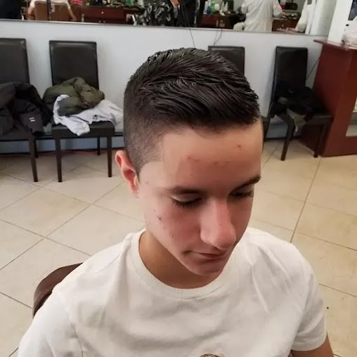 Young person with a faded haircut at a barbershop, facing down.
