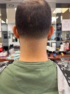 Man's neck and back of head with a faded haircut, in a barbershop setting.