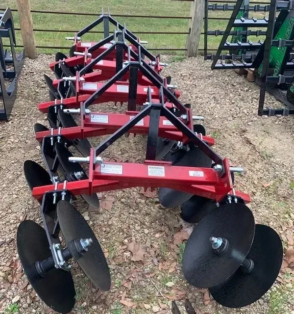 A row of disc plow tractors are lined up on the ground