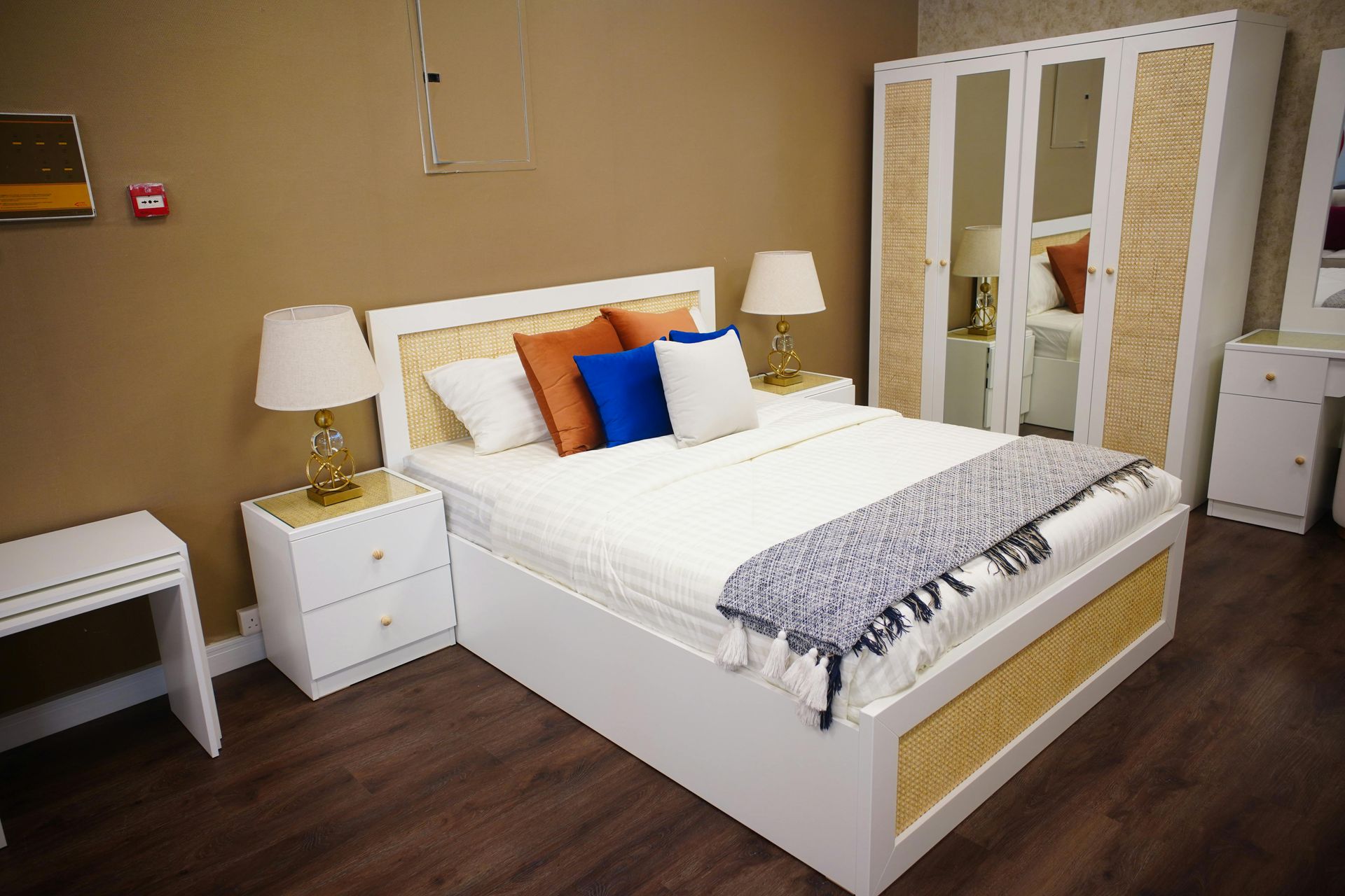 Bedroom set with white bed, nightstands, wardrobe, and desk. Brown and white tones, neutral decor.