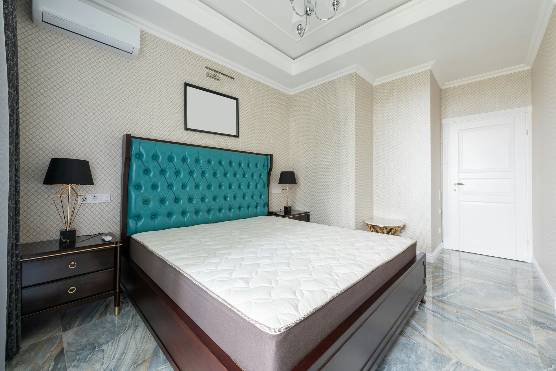 Bedroom with turquoise headboard, two black lamps, and marble flooring.