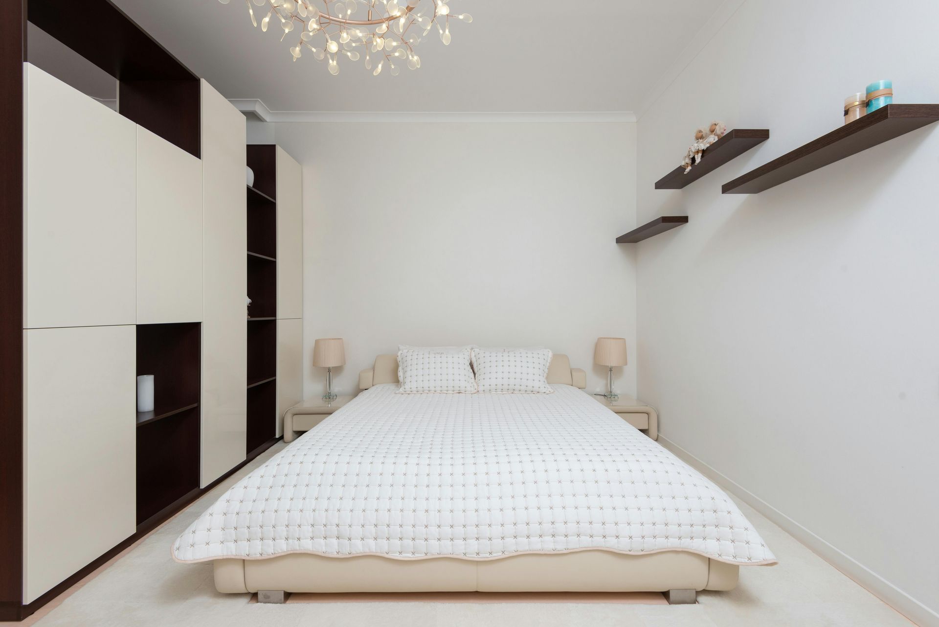Modern bedroom with white bed, built-in closet, and floating shelves.