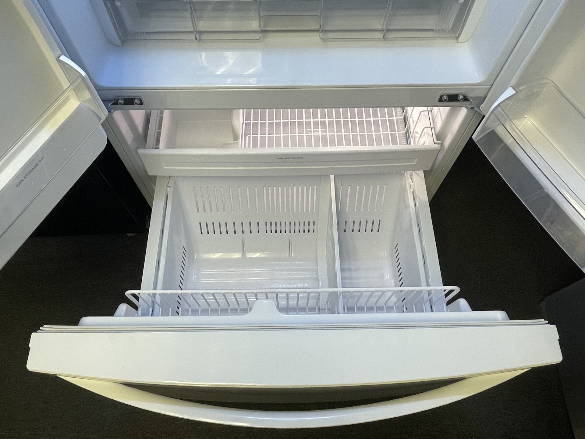The inside of a refrigerator with the door open and the freezer drawer open