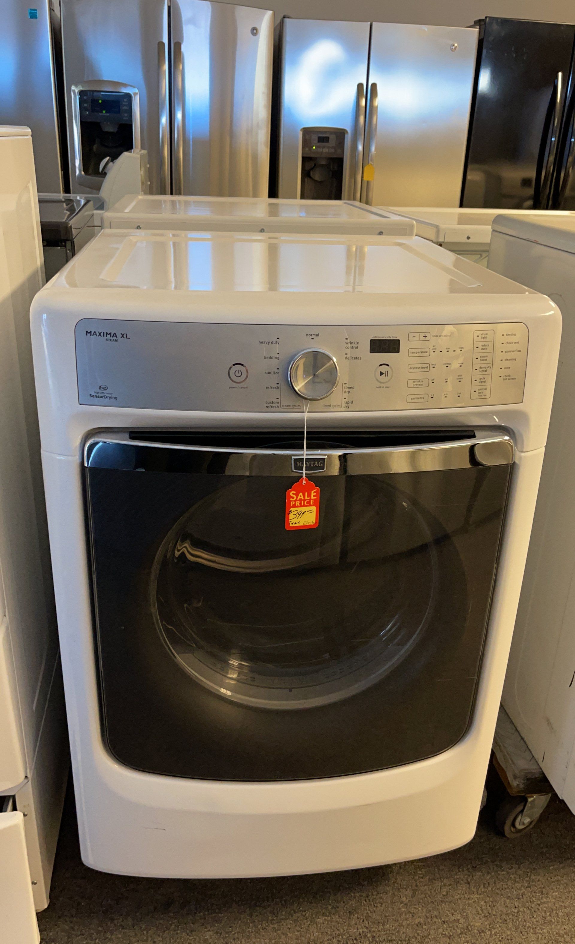 A white washer and dryer are sitting on a carpet in a store.