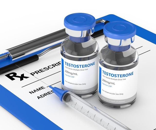 Two bottles of testosterone are on a clipboard next to a syringe