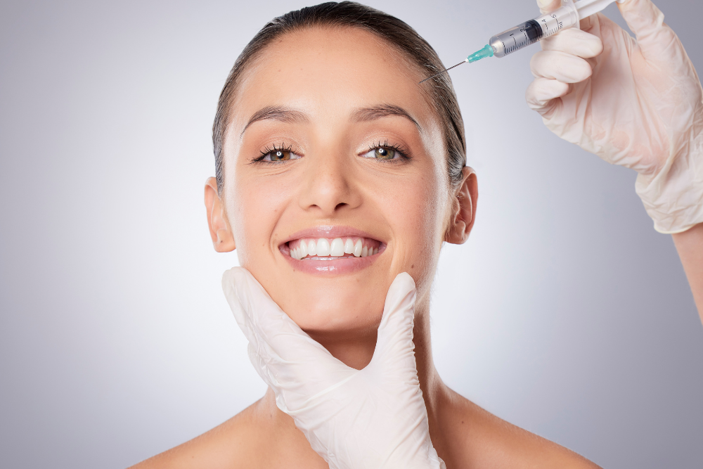 A woman is smiling while getting a botox injection in her face.